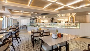 A modern restaurant interior with a central counter displaying pastries, surrounded by tables and chairs. - La Moon Puducherry (Puducherry)