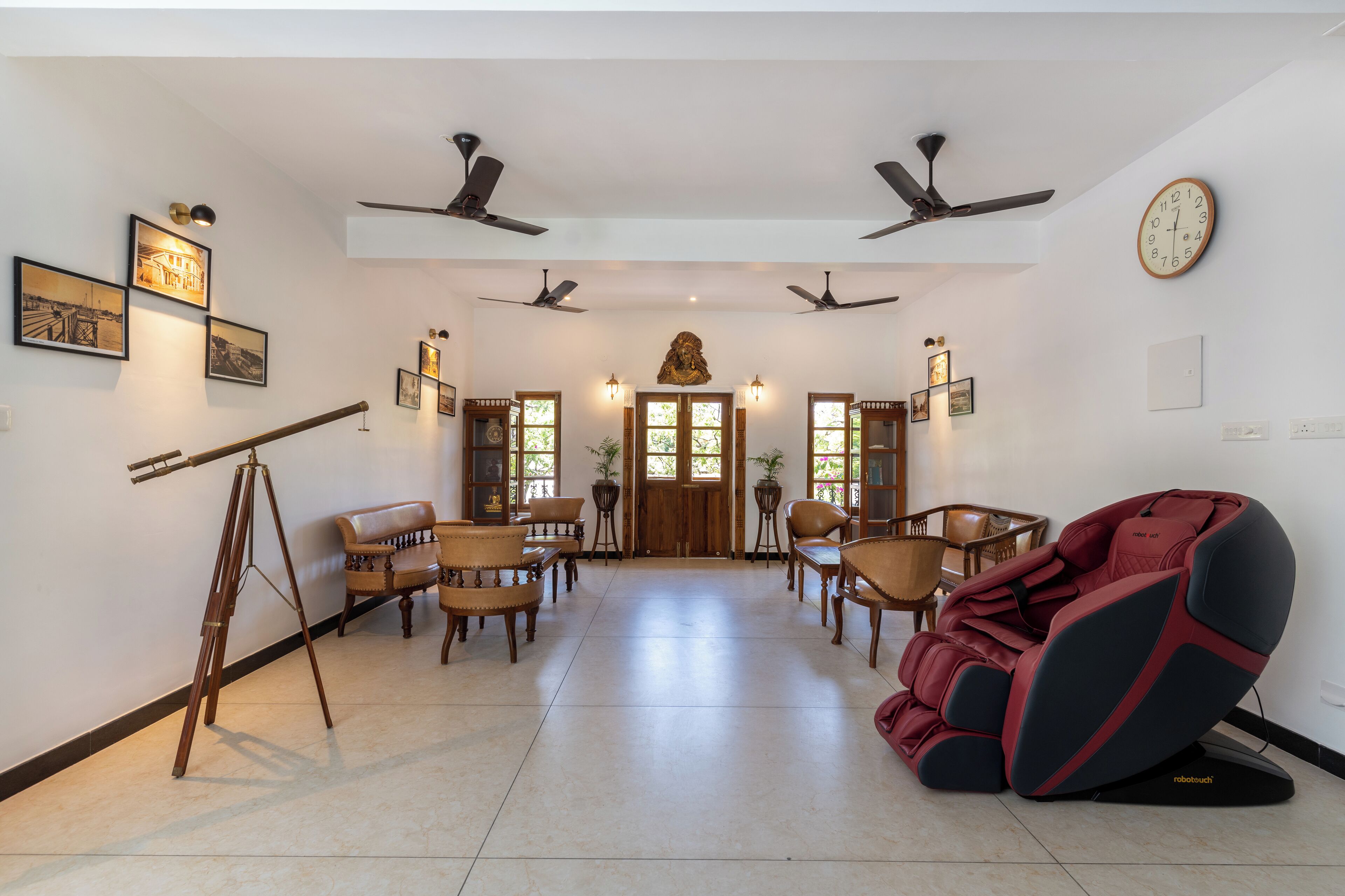 A spacious room with a wooden floor, a massage chair, ceiling fans, and framed pictures on the walls.