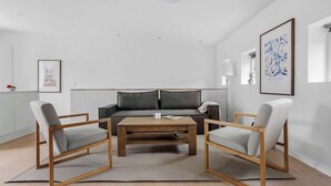 Ett modernt vardagsrum med en soffa, två fåtöljer, ett soffbord och en lampa.