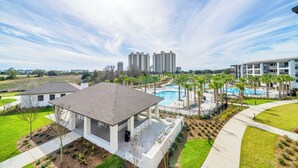 Zona residencial con piscina, palmeras y edificios modernos al fondo.