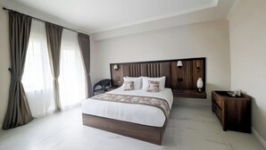 A modern hotel room with a large bed, a wooden headboard, a nightstand, and a chair. - Yashshree Resorts & Spa Kalimpong (Kalimpong)