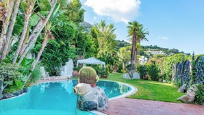 A pool with a cactus sculpture, surrounded by lush greenery and a white gazebo. - Charming One-Bedroom Apartment with Sea View in Villa with Pool by the Sea (Forio)