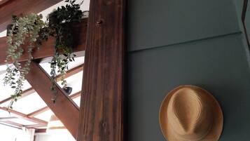 Estructura de techo de madera con plantas colgantes y un sombrero de paja en una pared.