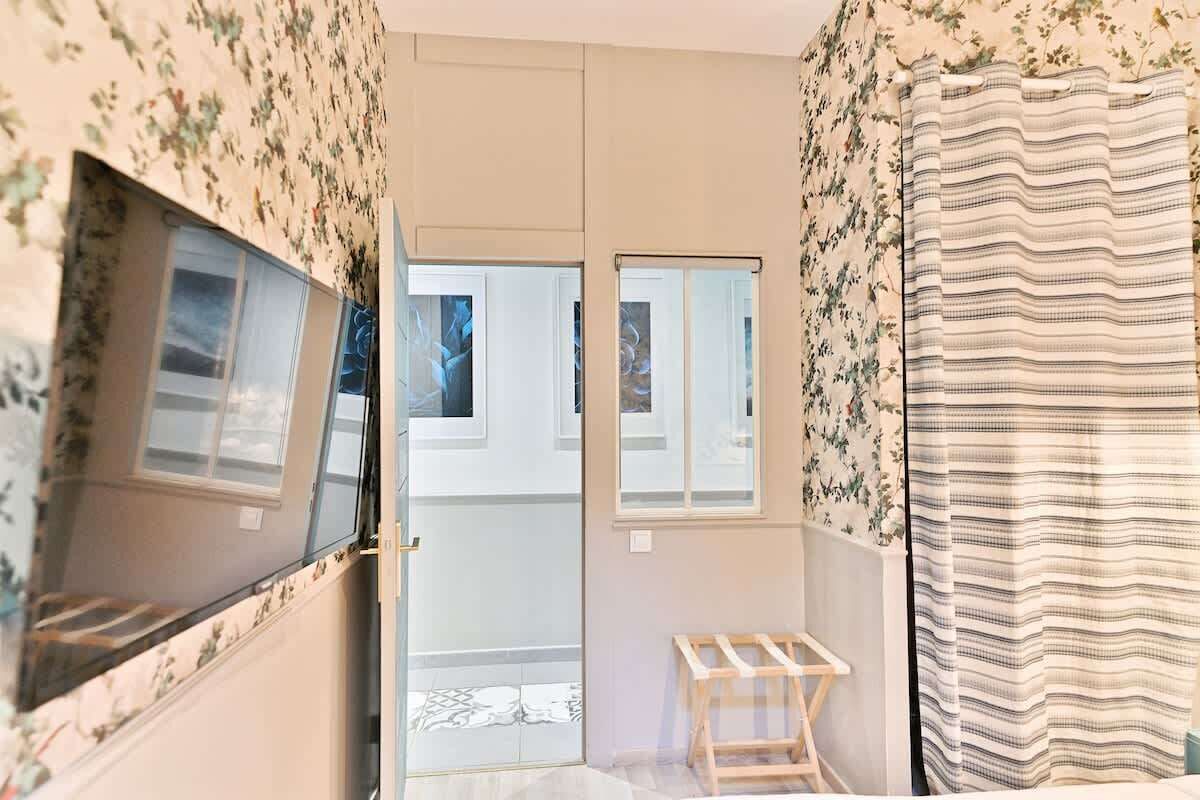 A bathroom with floral wallpaper, a shower curtain, and a wooden bench.