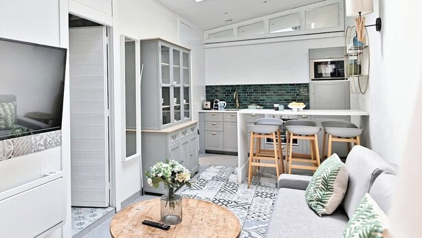 A modern kitchen with a skylight, a dining area with stools, and a living space with a sofa and a coffee table. - Superbe appartement lumineux 6P (Paris)