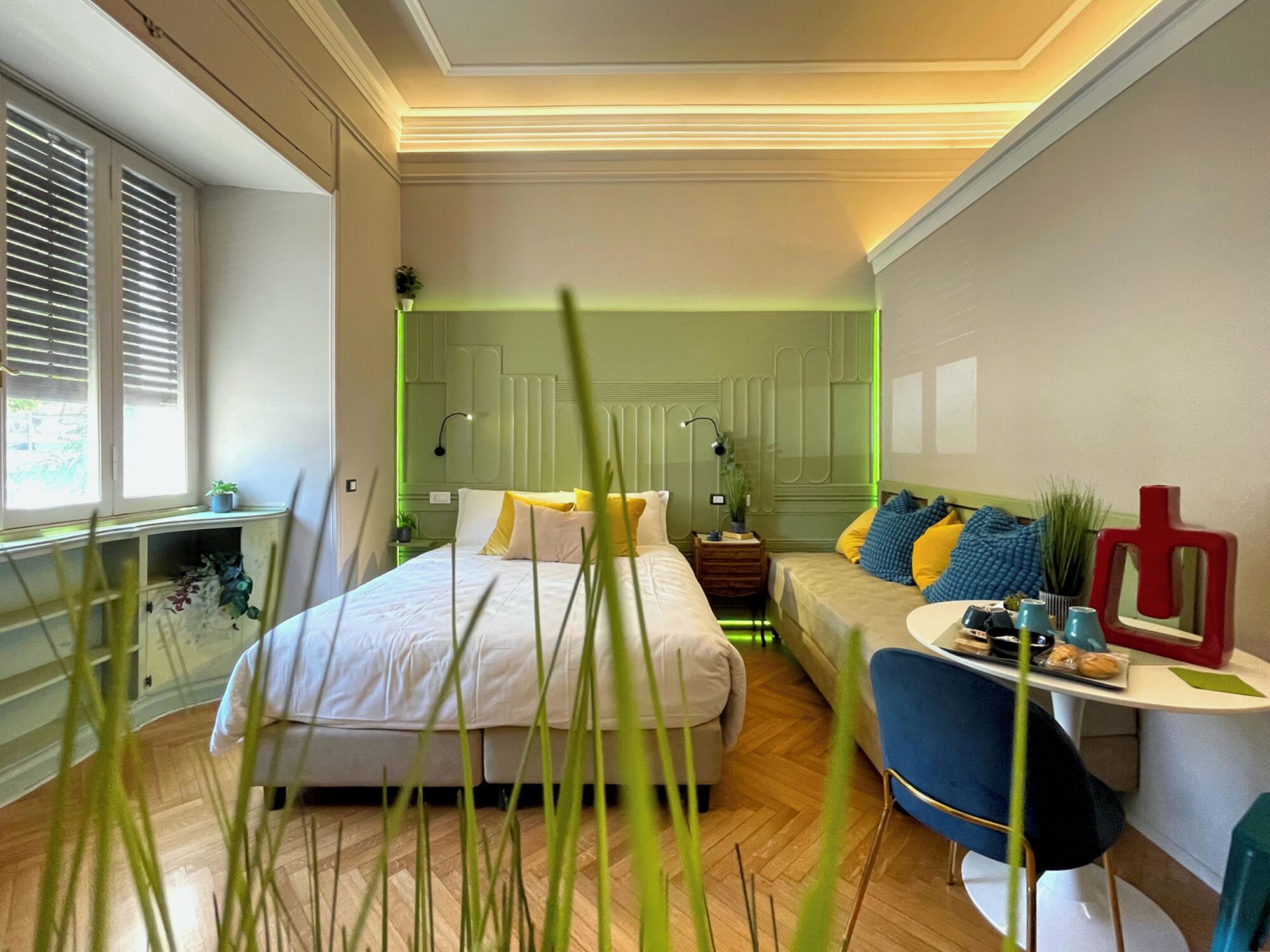 Ein modernes Schlafzimmer mit Bett, einer Couch, einem kleinen Tisch und einem Spiegel.