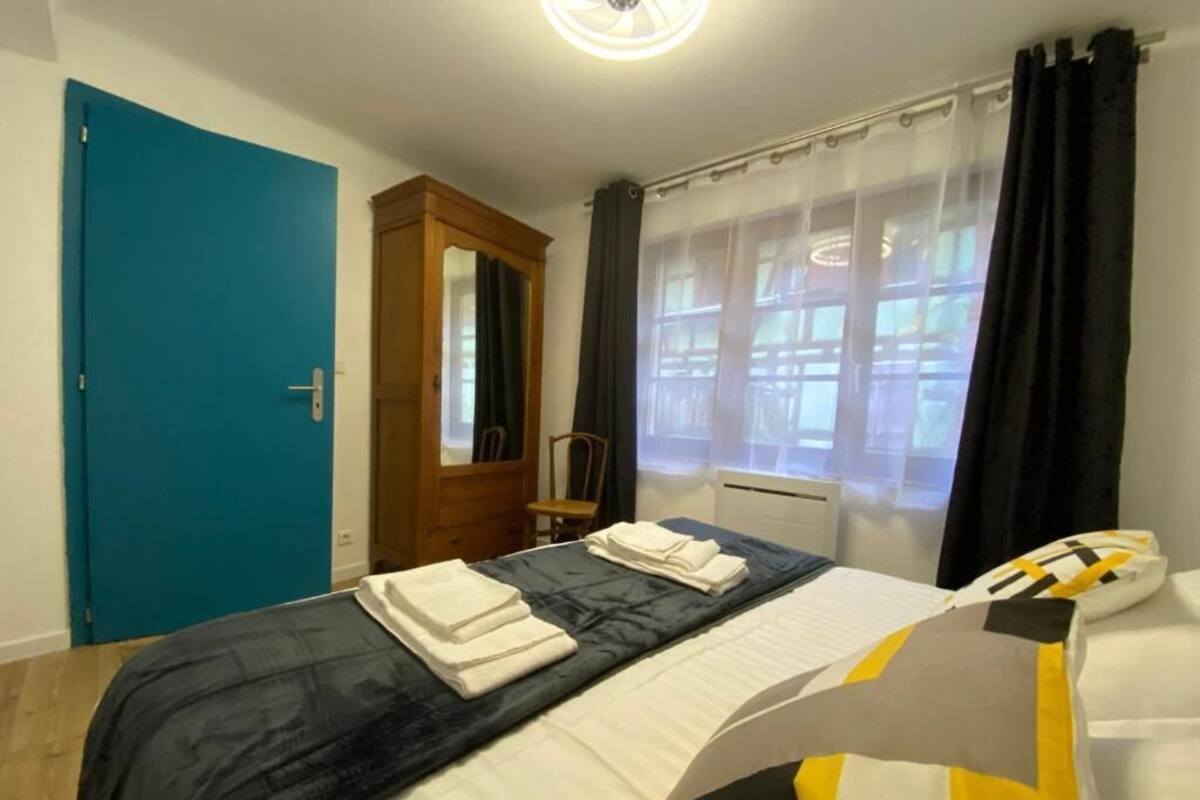 Une chambre d’hôtel avec un lit, une armoire, une chaise et une fenêtre avec des rideaux.