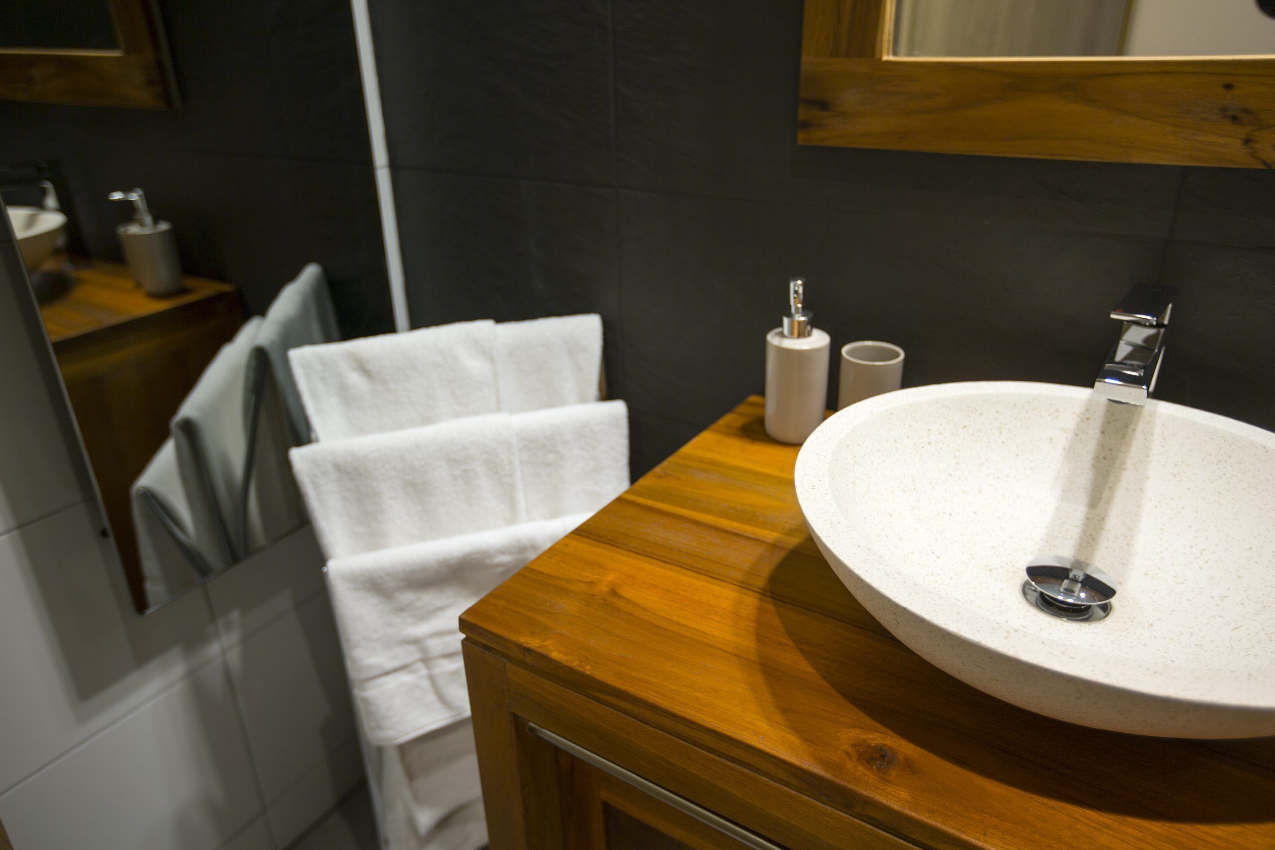 A bathroom with a wooden vanity, a white sink, and a mirror above it.