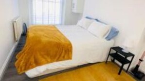 Une chambre à coucher avec un lit, une table de chevet et une fenêtre avec des stores.