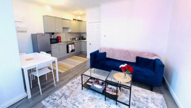Un espace de vie compact comprenant un coin cuisine, un coin repas et un espace détente avec un canapé et une table basse.