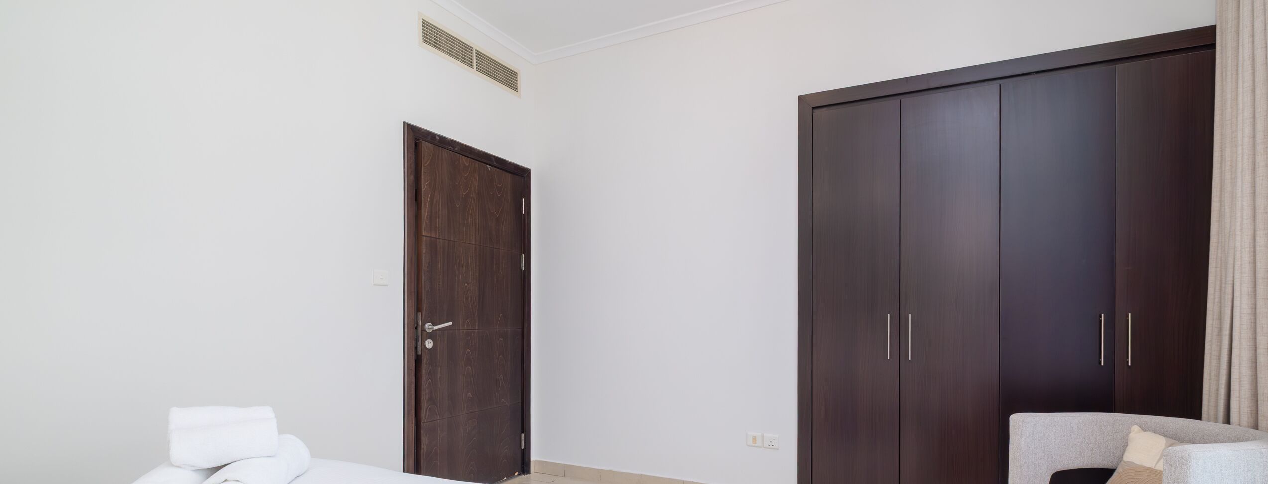 A bedroom with a bed, a wardrobe, and a chair.