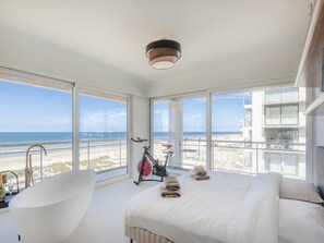 A hotel room with a large window offering a view of the beach and ocean. - Apartment With Panoramic sea View in De Panne (Koksijde)