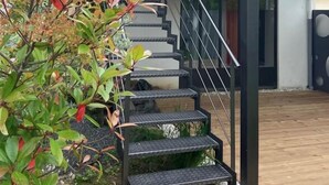 Un escalier moderne avec une rampe en métal menant à un balcon situé au deuxième étage.