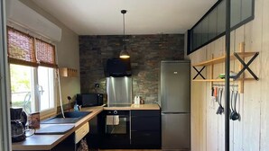 Une cuisine de taille réduite avec un dosseret en pierre, des appareils électroménagers en acier inoxydable et un plancher en bois.