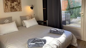 Une chambre avec un grand lit, un tableau au mur, une fenêtre avec des rideaux et une vue sur l’extérieur.