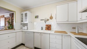 A modern kitchen with white cabinetry, a dishwasher, a sink, and a stove.