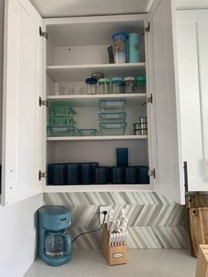 Uma cozinha com armário embutido contendo recipientes de armazenamento, cafeteira e porta-facas.