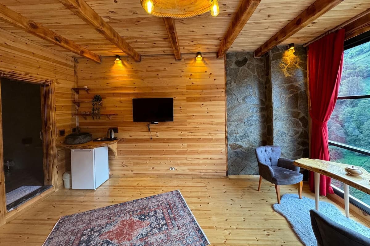 Un intérieur en bois avec un mur en pierre, une télévision, une table à manger et une chaise.