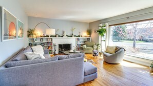 A modern living room with a grey sofa, a round coffee table, and a fireplace. There are bookshelves and decorative plants. - 24 Mi to Slopes! Family Reno Home w/ Outdoor Oasis (Reno)