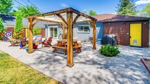 A wooden pergola with picnic tables, a barbecue grill, and a yellow door. - 24 Mi to Slopes! Family Reno Home w/ Outdoor Oasis (Reno)