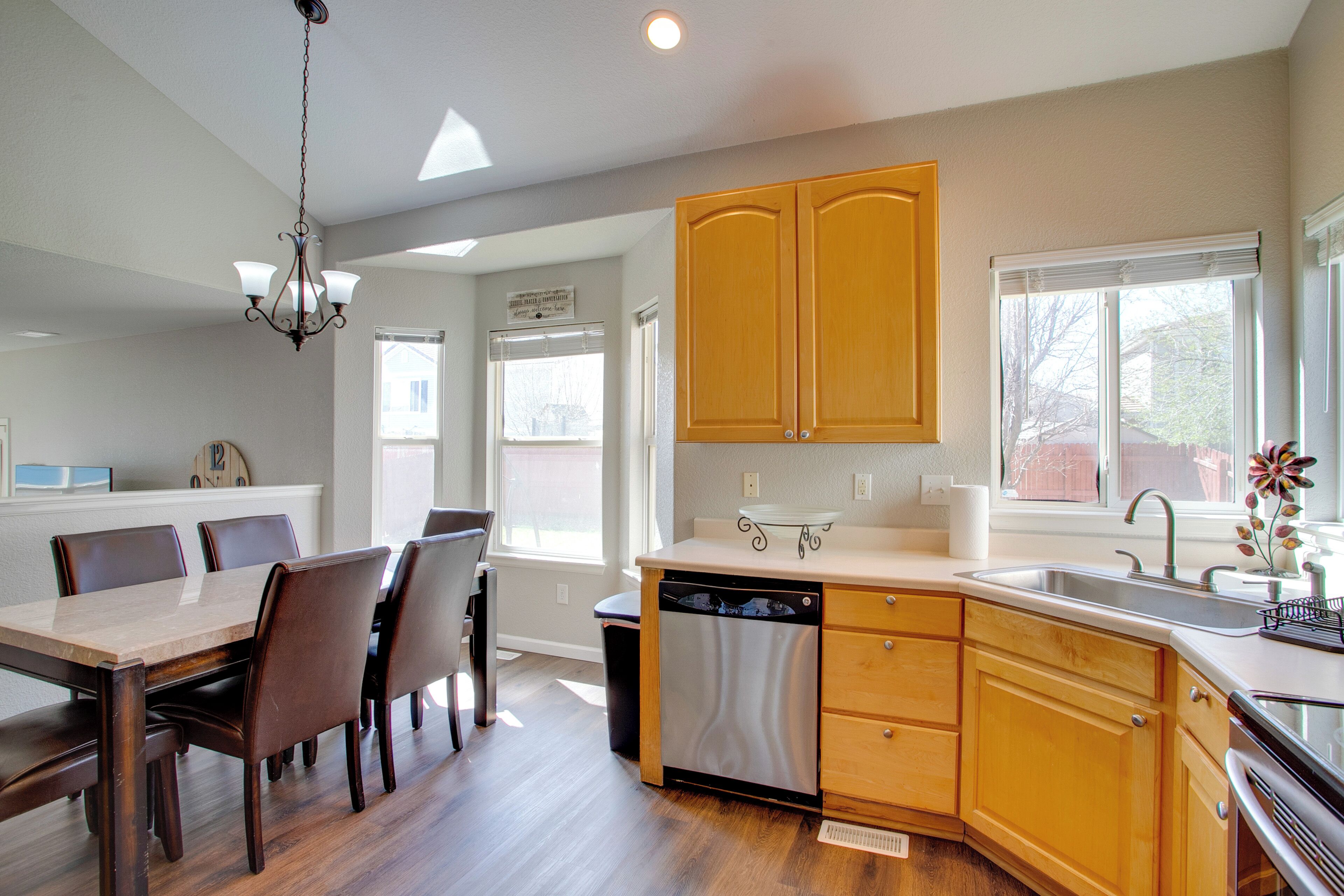 A kitchen with wooden cabinets, a dishwasher, and a dining area with chairs.