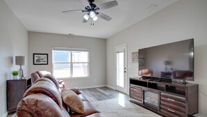 A spacious living room with a leather sofa, a flat-screen TV, and a ceiling fan. - 17 Mi to Dtwn Denver: Family Home w/ Private Yard (Commerce City)