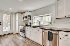 A modern kitchen with white cabinets, stainless steel appliances, and a window with a view of the outdoors. - 14 Mi to Pearl Street Mall: Erie Getaway (Erie)