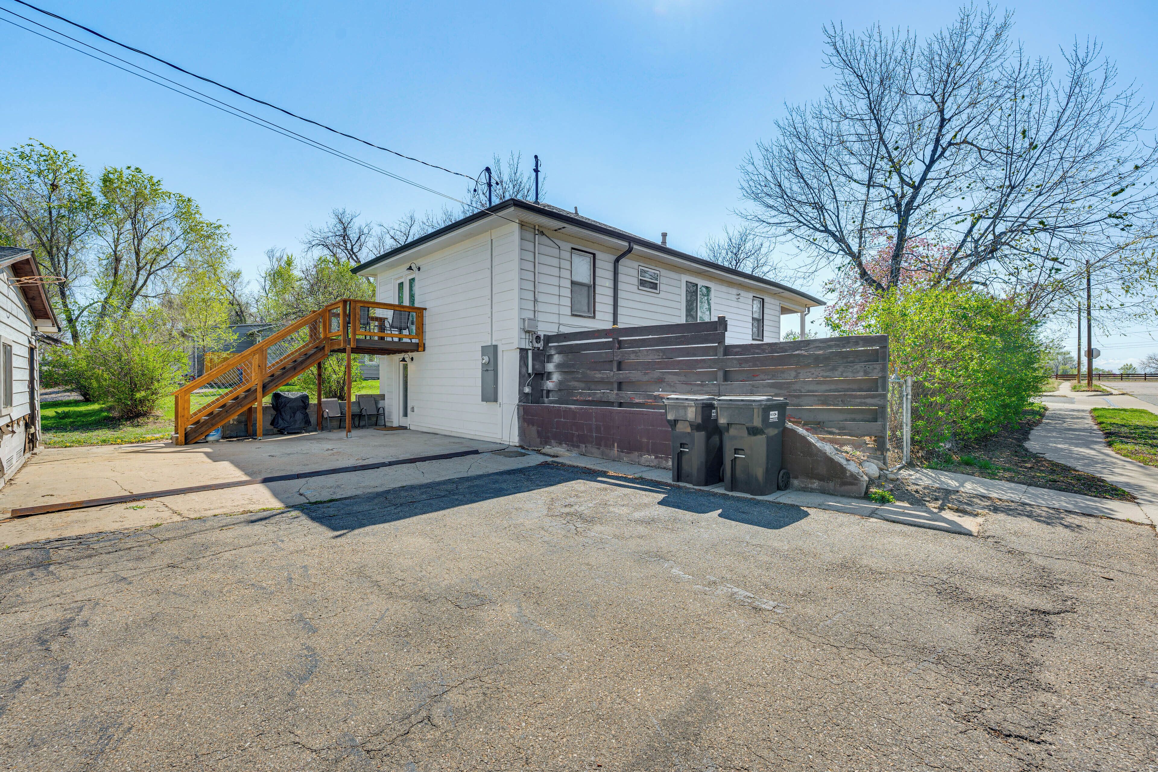 A single-story house with a covered porch, a wooden staircase, and a gated driveway.