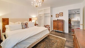 Un dormitorio con una cama grande, un aparador de madera, un candelabro y un vestidor.