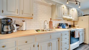 Una cocina moderna con armarios blancos, horno integrado y cafetera.