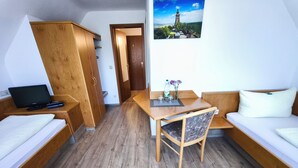 Une petite pièce comprenant un lit, un bureau, une chaise et une petite table.