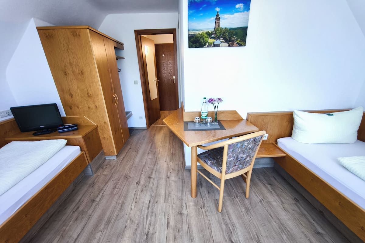 Ein gemütlicher Raum mit einem Bett, einem Schreibtisch, einem Stuhl und einem kleinen Tisch.