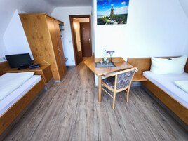 Quarto compacto com cama, escrivaninha, cadeira e mesa pequena.