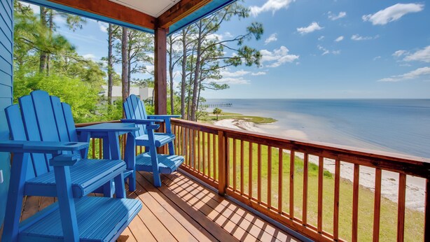 A wooden deck with blue Adirondack chairs overlooking a beach and ocean. - Beachfront Retreat w/ Dock in Lanark Village! (Carrabelle)