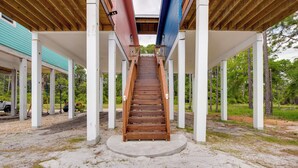 A wooden staircase leading up to a covered area with white pillars and a sandy ground. - Beachfront Retreat w/ Dock in Lanark Village! (Carrabelle)