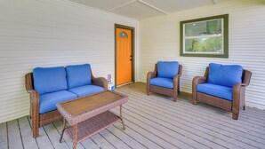 Une véranda couverte, aménagée avec des meubles en osier et une table en bois.