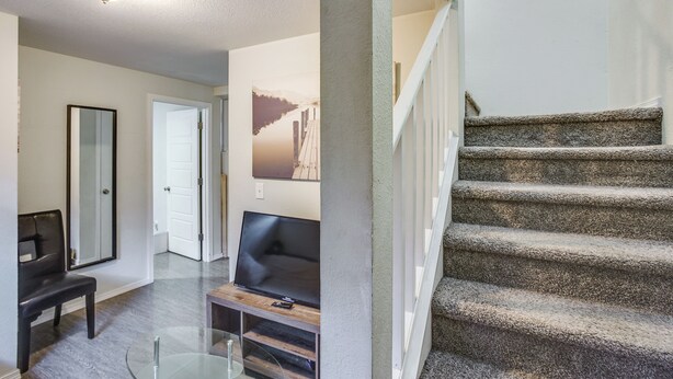 A modern interior with a staircase, a flat-screen TV, and a glass table. - 3 Mi to Dtwn Tacoma: Pet-friendly Home (Tacoma)
