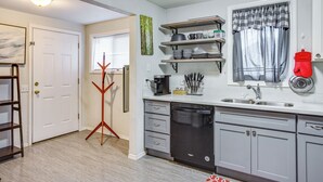 A kitchen with a dishwasher, shelves with kitchenware, a window with curtains, and a coat rack. - 3 Mi to Dtwn Tacoma: Pet-friendly Home (Tacoma)