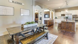 A spacious kitchen with white cabinets, a wooden island, and a dining area with a bench. - Balcony & Patio: Spacious Home in Bel Aire! (Wichita)