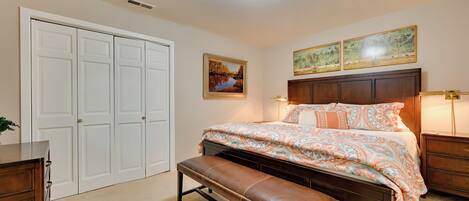 Une chambre à coucher avec un grand lit, un banc, une commode, une armoire et deux lampes fixées au mur.