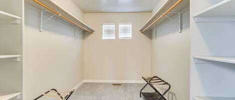 A walk-in closet with white shelving, a wooden bench, and a metal bench.