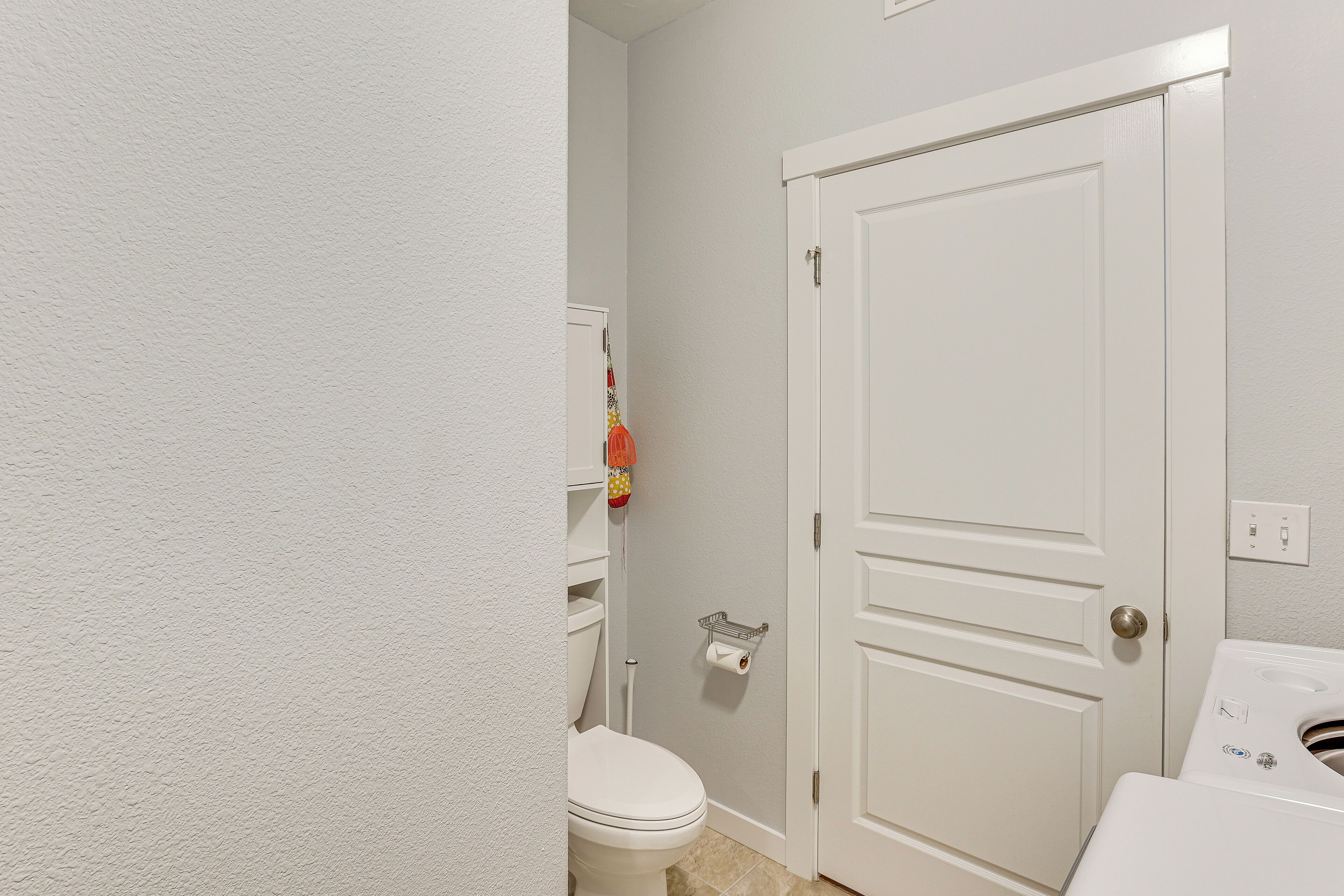 Een badkamer met een toilet, een witte deur en een wasmachine.