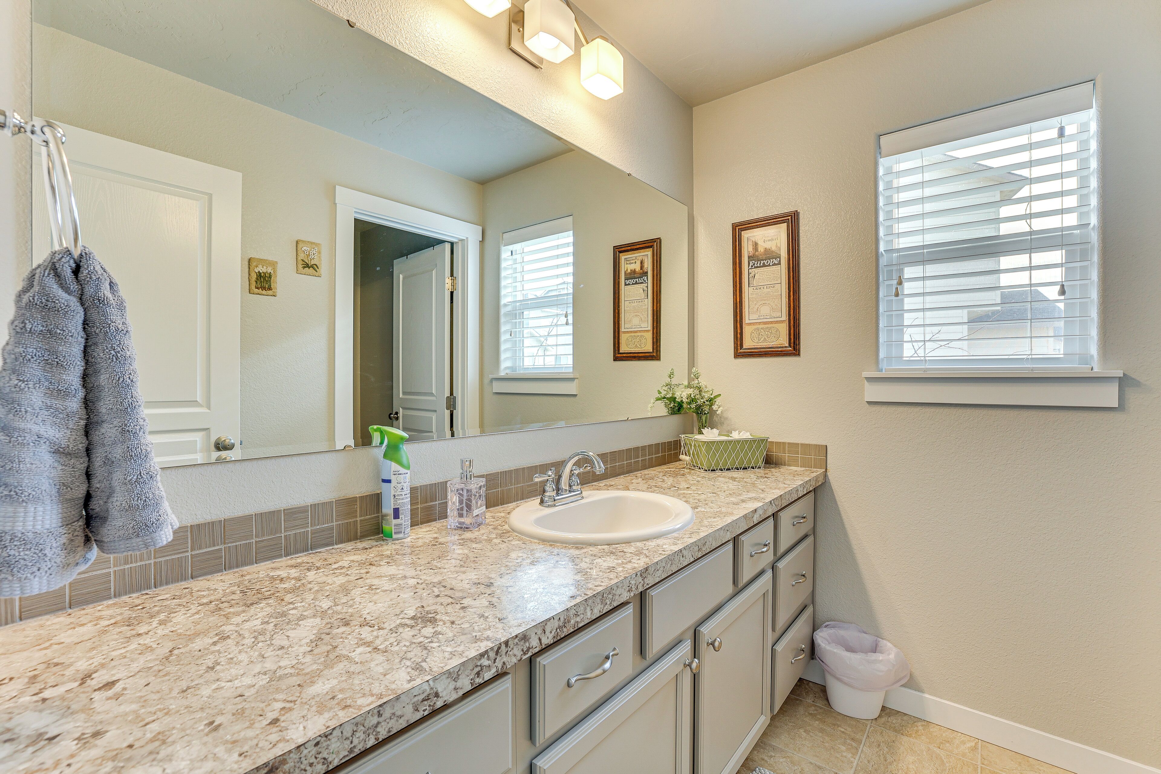A bathroom with a sink, mirror, towel rack, and framed pictures on the wall.
