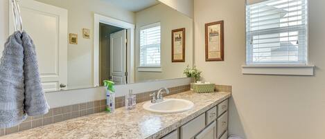 A bathroom with a sink, mirror, towel rack, and framed pictures on the wall.