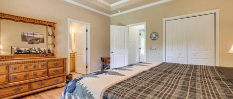 Een slaapkamer met een groot bed, een houten dressoir en een plafondventilator.