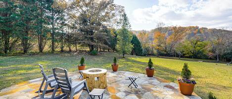 A patio with stone flooring, outdoor seating, and potted plants.