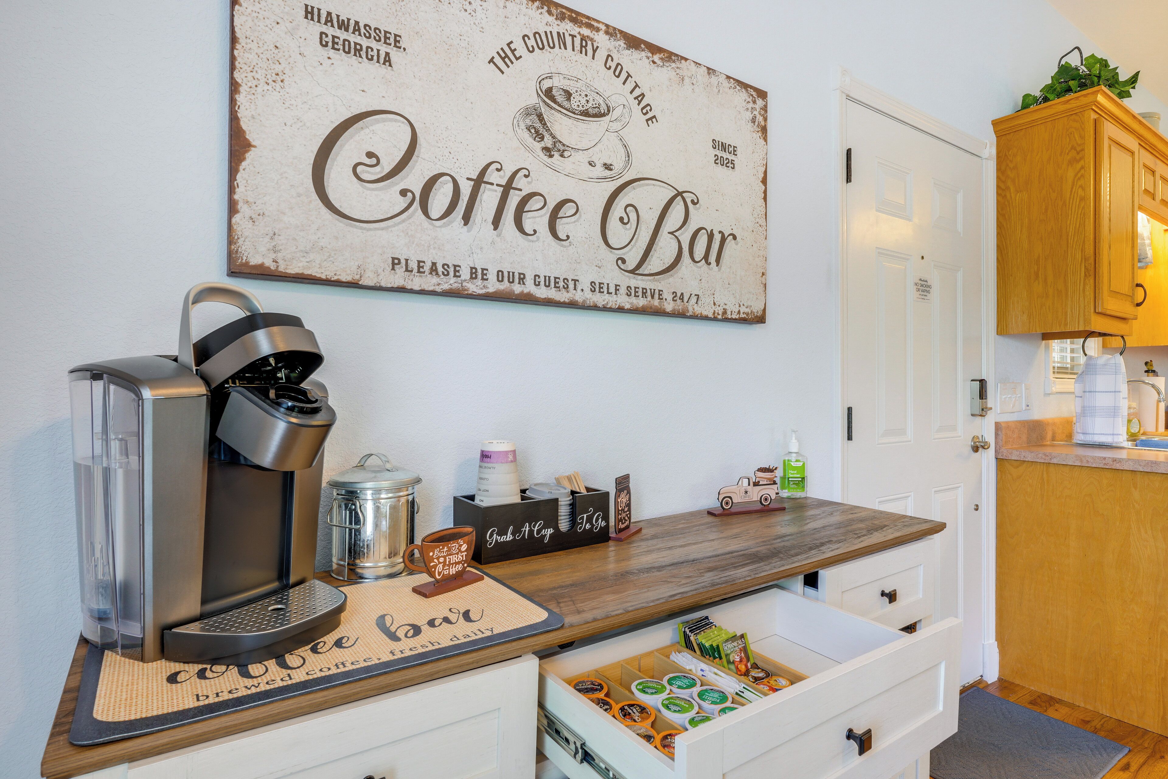 A coffee bar setup with a coffee machine, mugs, and a sign that reads "Coffee Bar".