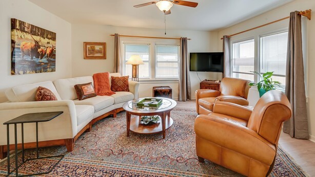 A living room with a sofa, armchair, coffee table, and a ceiling fan.