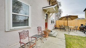 A patio with outdoor furniture, including chairs and a table, and a barbecue grill.
