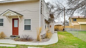 A two-story house with a red door, a small porch, and a fenced backyard.